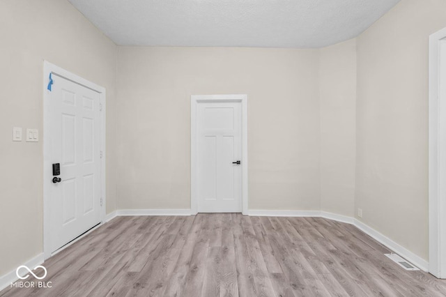 spare room with light hardwood / wood-style floors and a textured ceiling