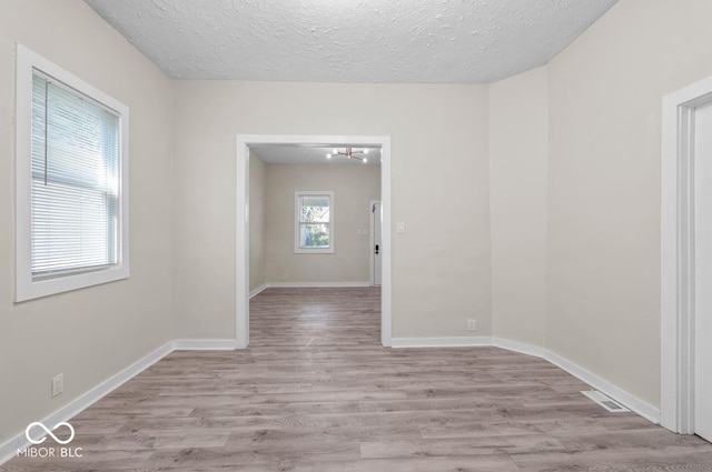 unfurnished room featuring light hardwood / wood-style floors and a textured ceiling