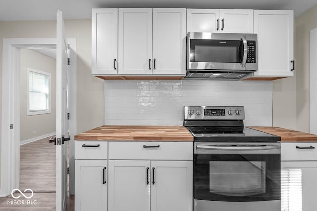 kitchen with white cabinetry, wooden counters, hardwood / wood-style flooring, stainless steel appliances, and decorative backsplash