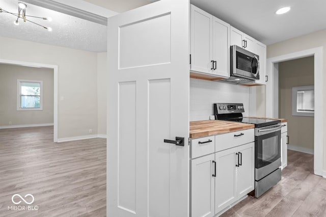 kitchen featuring butcher block counters, stainless steel appliances, light hardwood / wood-style floors, decorative backsplash, and white cabinets