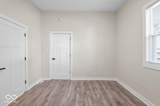 empty room with plenty of natural light and light hardwood / wood-style floors