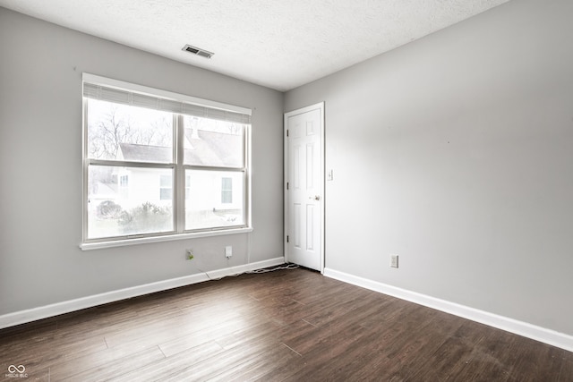 empty room with dark wood-type flooring and a textured ceiling