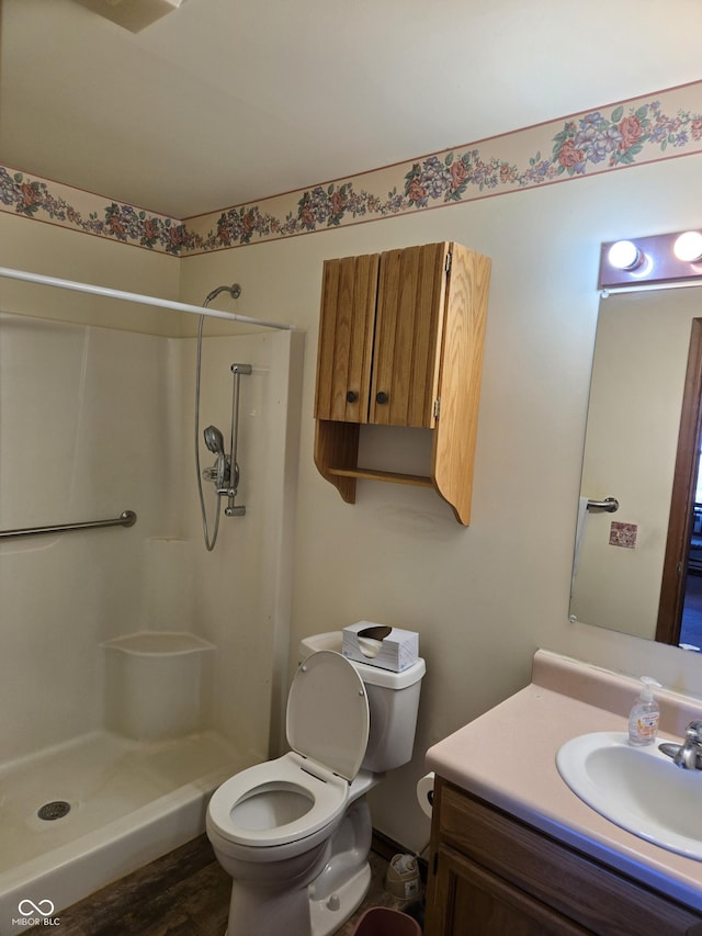 bathroom featuring hardwood / wood-style flooring, a shower, vanity, and toilet