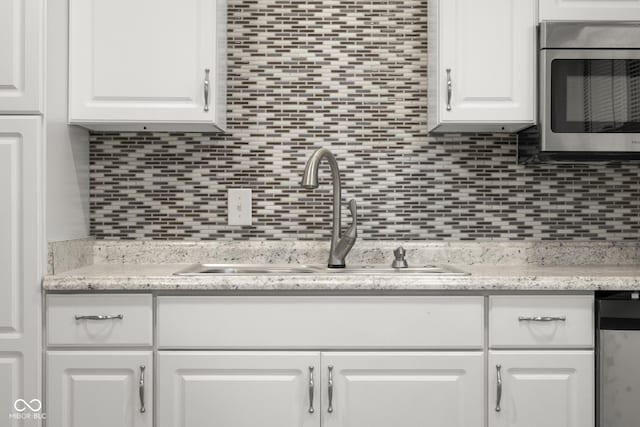 kitchen featuring sink, decorative backsplash, and white cabinets