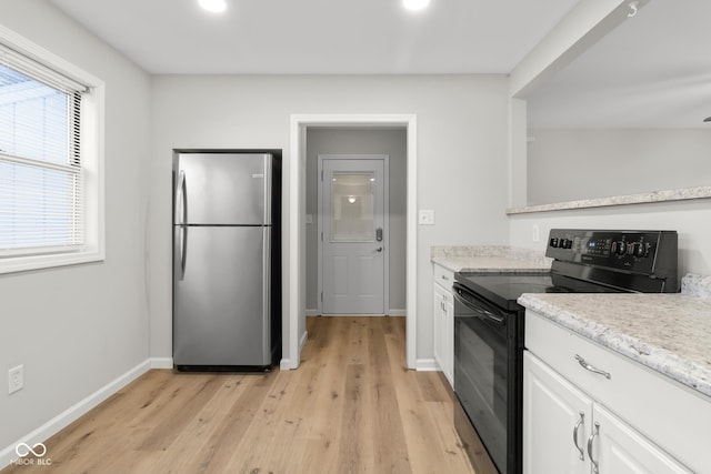 kitchen featuring light hardwood / wood-style flooring, black / electric stove, stainless steel fridge, light stone countertops, and white cabinets