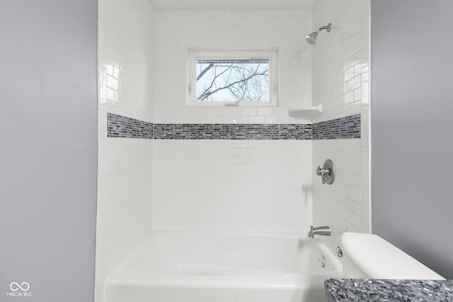 bathroom with toilet and tiled shower / bath