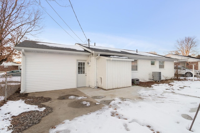 snow covered back of property featuring central air condition unit