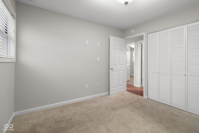 unfurnished bedroom with multiple windows, light carpet, and a closet