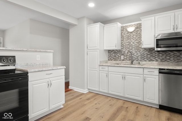 kitchen with sink, white cabinets, light hardwood / wood-style floors, stainless steel appliances, and light stone countertops