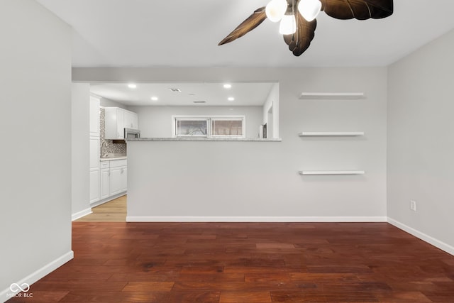 unfurnished living room featuring dark wood-type flooring and ceiling fan