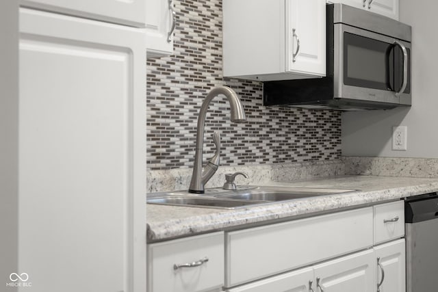 kitchen with white cabinetry, backsplash, stainless steel appliances, and sink