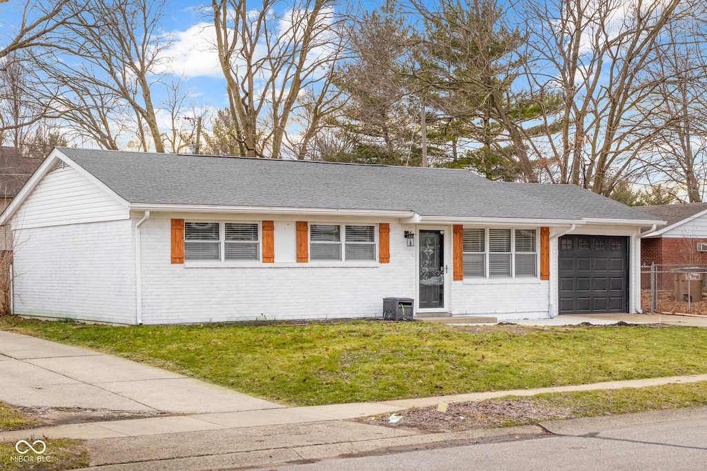 ranch-style house featuring a garage, central AC, and a front lawn