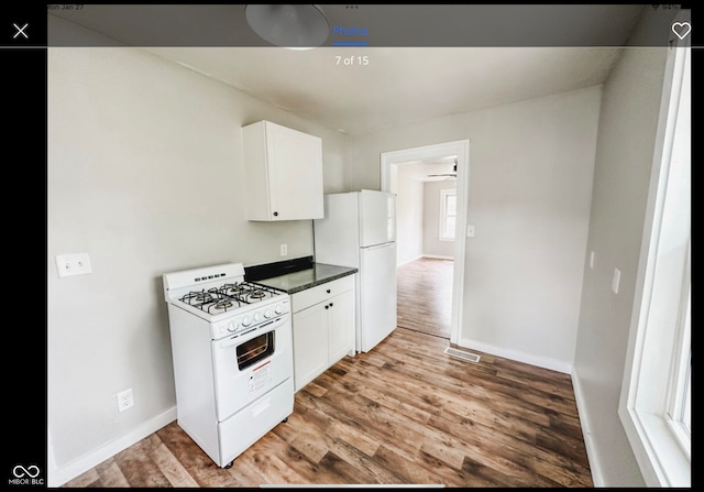 kitchen with white cabinetry, white appliances, and wood-type flooring