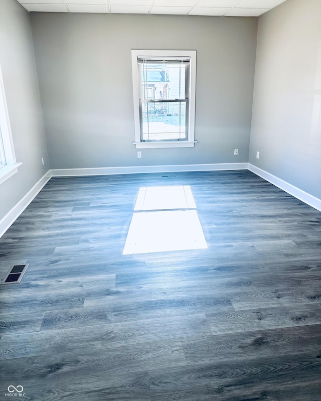 unfurnished room featuring a paneled ceiling and dark hardwood / wood-style flooring