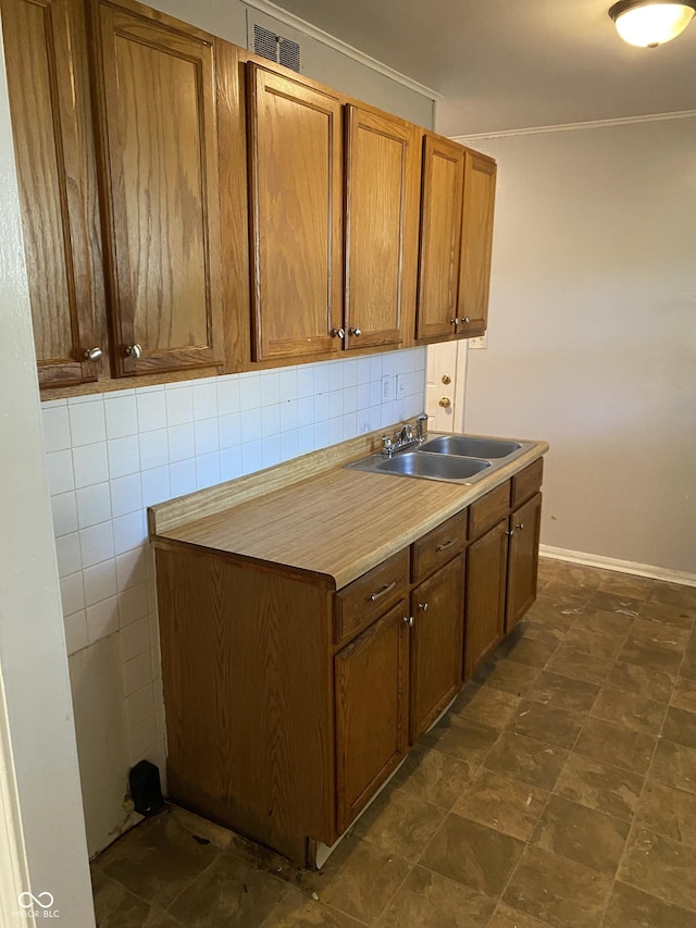 kitchen with crown molding, sink, and tasteful backsplash
