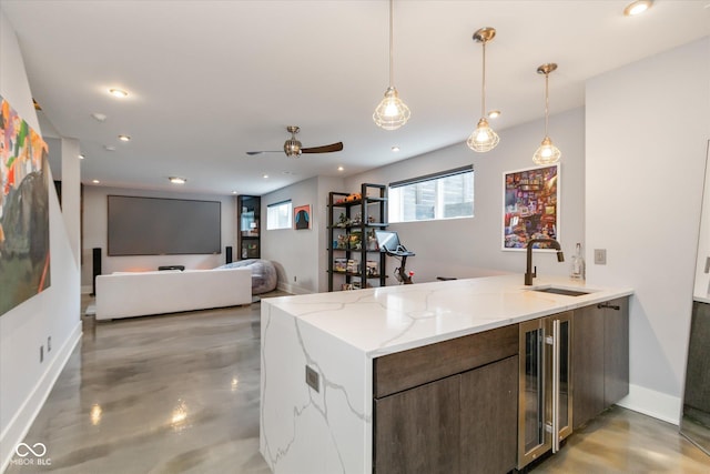 kitchen featuring decorative light fixtures, sink, beverage cooler, kitchen peninsula, and light stone countertops