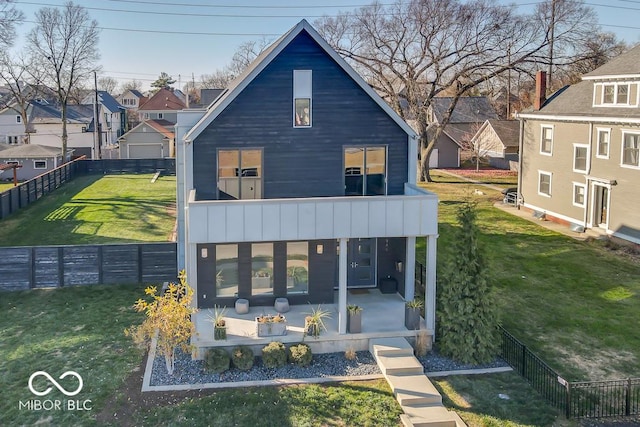 back of house with a balcony, a patio area, and a lawn