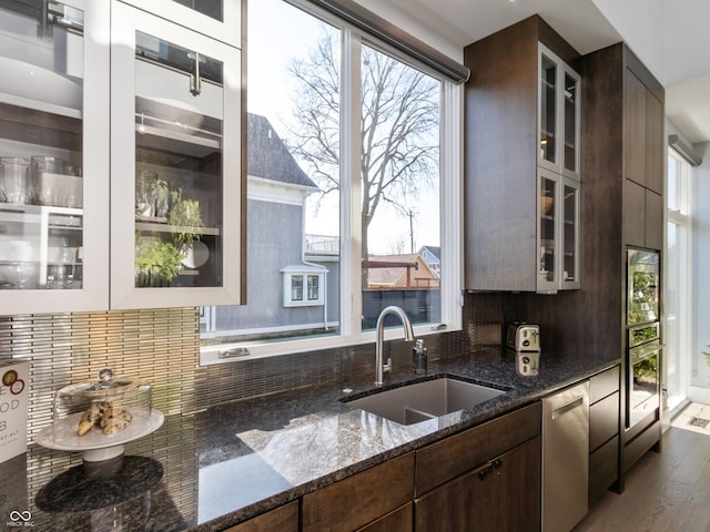 kitchen featuring appliances with stainless steel finishes, sink, dark stone countertops, decorative backsplash, and dark brown cabinets