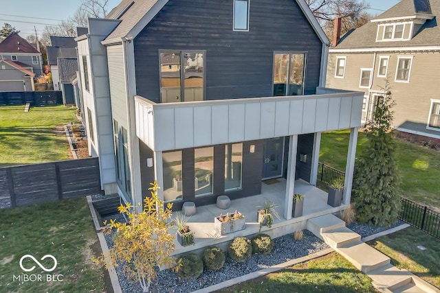 back of house with a balcony, a yard, and a patio area