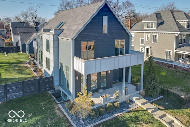 rear view of house with a yard, a patio, and a balcony