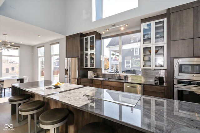 kitchen featuring sink, a breakfast bar area, dark stone countertops, backsplash, and stainless steel appliances