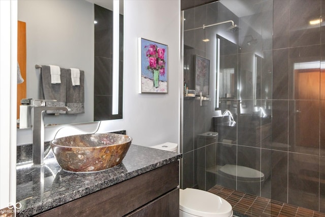 bathroom featuring vanity, toilet, and tiled shower