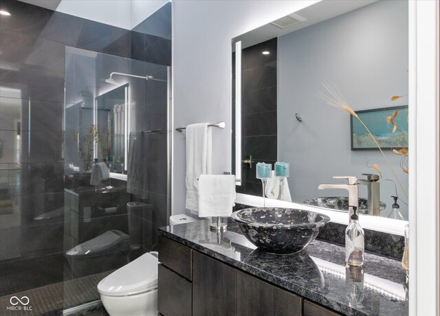 bathroom with vanity, toilet, and tiled shower