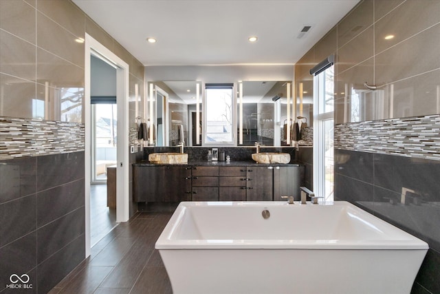 bathroom with vanity, a tub, and tile walls