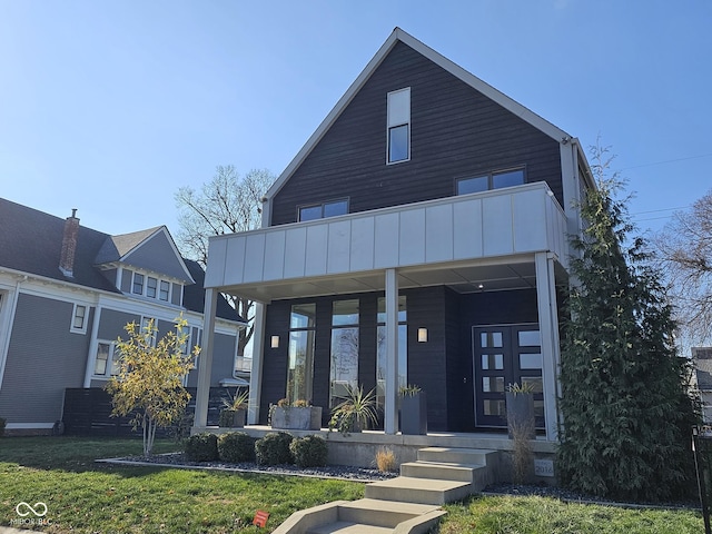 view of front facade featuring a balcony, covered porch, and a front yard