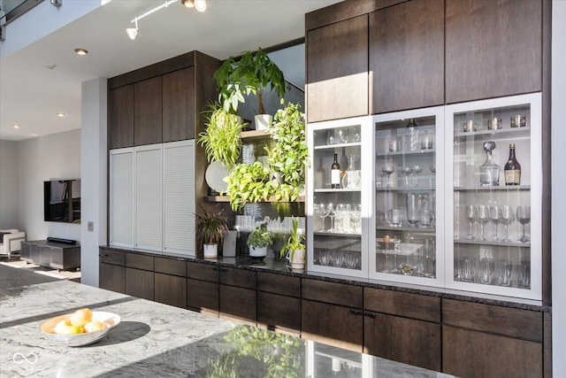 bar featuring dark brown cabinetry and dark stone countertops