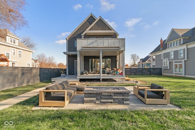 back of house featuring a patio, a balcony, a yard, and a fire pit