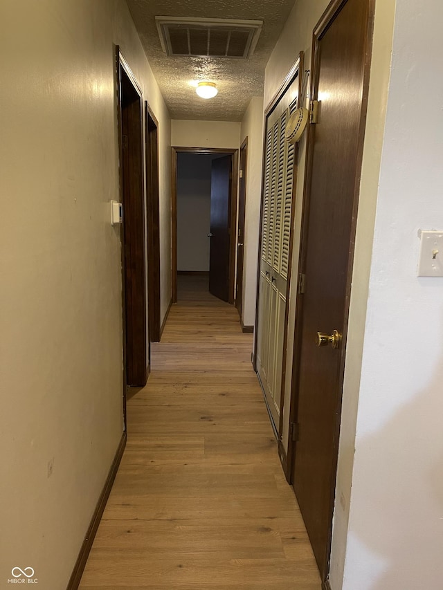 hall featuring a textured ceiling and light wood-type flooring