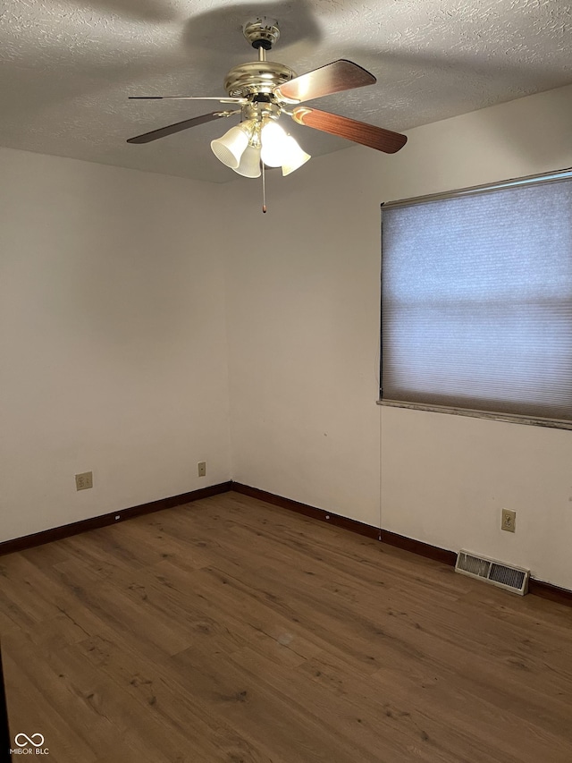 empty room featuring ceiling fan, dark wood-type flooring, and a textured ceiling