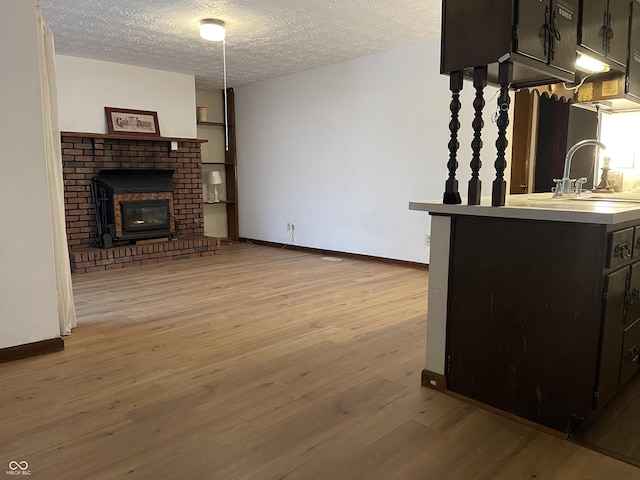 living room with sink, a fireplace, a textured ceiling, and light hardwood / wood-style flooring