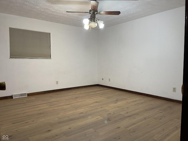 empty room featuring ceiling fan, hardwood / wood-style flooring, and a textured ceiling