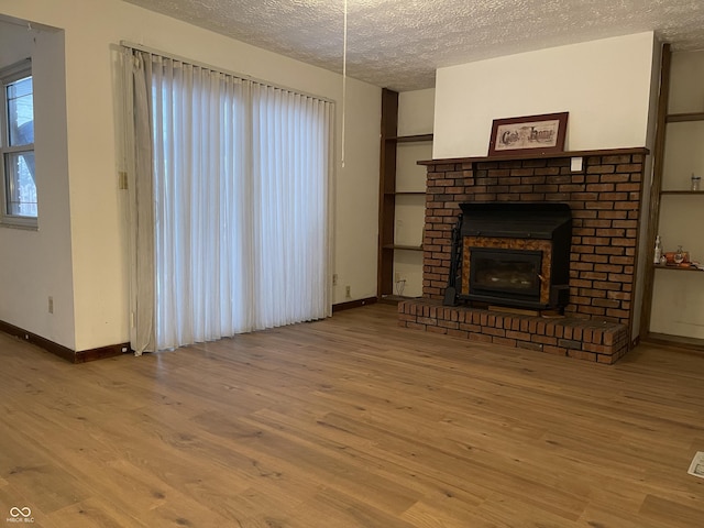 unfurnished living room featuring a textured ceiling, light wood-type flooring, and a fireplace