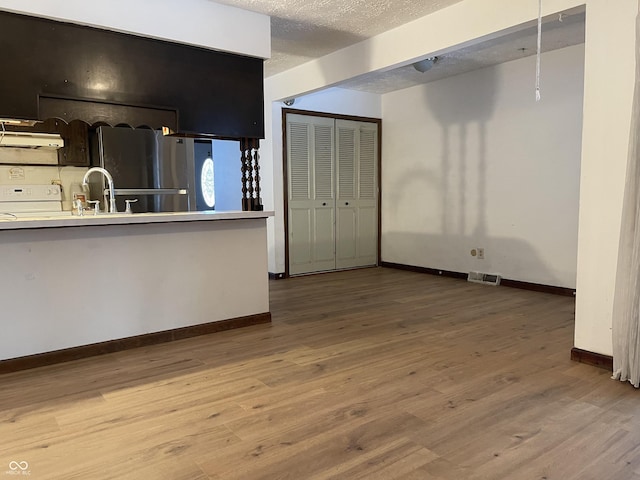 kitchen featuring hardwood / wood-style floors, sink, stainless steel fridge, white stove, and a textured ceiling