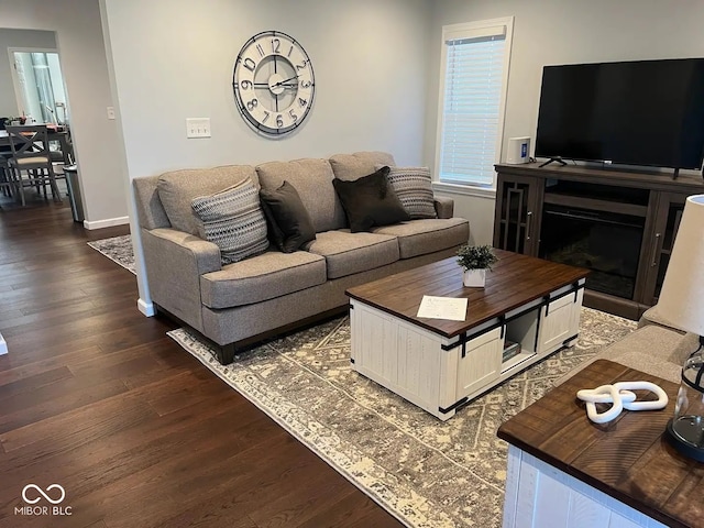 living area featuring a fireplace, dark wood-type flooring, and baseboards