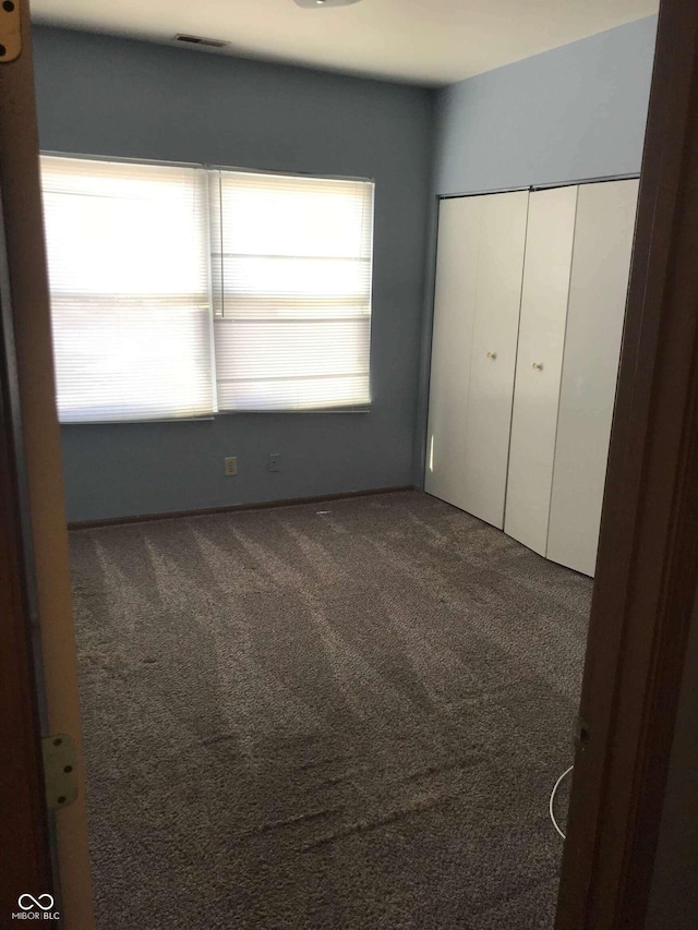 unfurnished bedroom with a closet and dark colored carpet