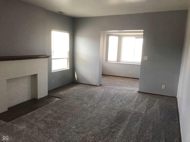 unfurnished living room featuring dark carpet and a healthy amount of sunlight