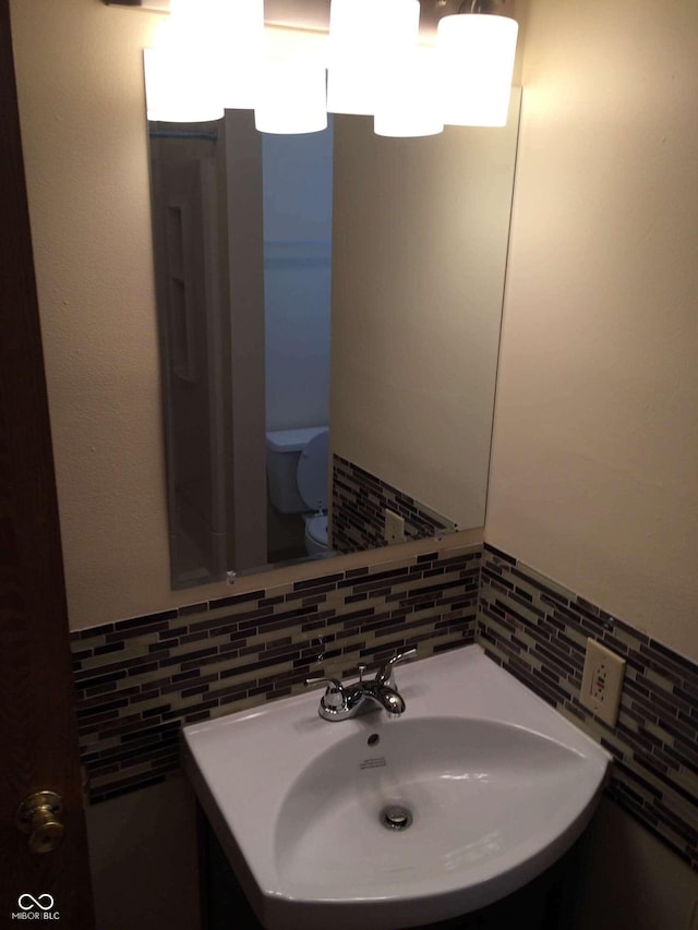 bathroom featuring toilet, sink, and decorative backsplash