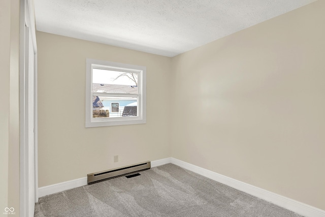 carpeted spare room with a textured ceiling and a baseboard heating unit