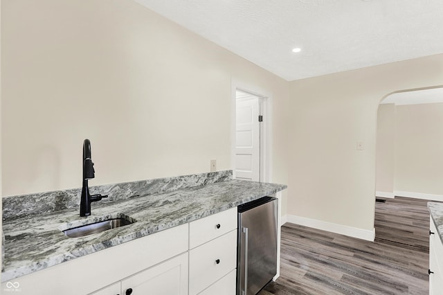 kitchen with light stone counters, refrigerator, sink, and white cabinets