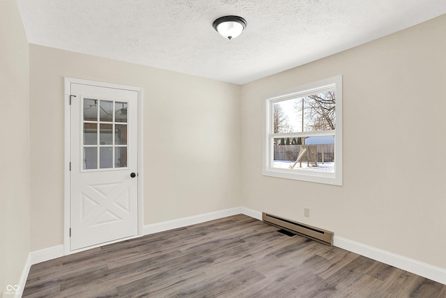 spare room featuring hardwood / wood-style floors, a textured ceiling, and baseboard heating