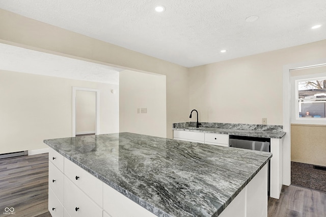 kitchen featuring white cabinetry, a kitchen island, dark hardwood / wood-style flooring, and dark stone counters