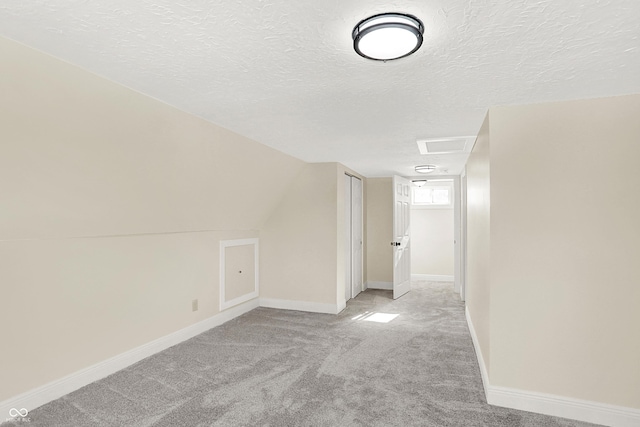 additional living space with light carpet, vaulted ceiling, and a textured ceiling