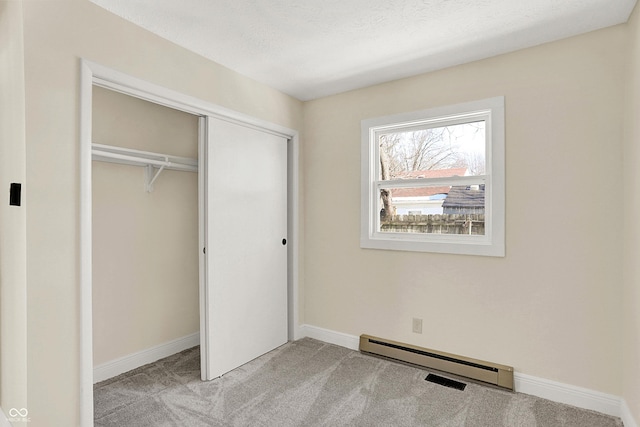 unfurnished bedroom featuring baseboard heating, light colored carpet, a closet, and a textured ceiling