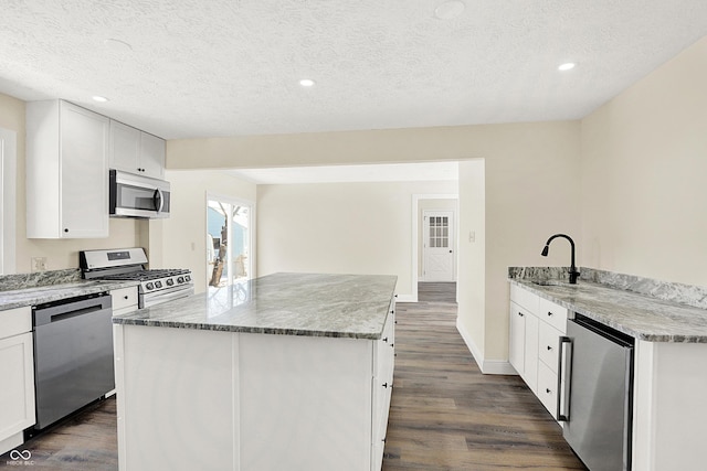 kitchen featuring white cabinetry, stainless steel appliances, a textured ceiling, and a kitchen island