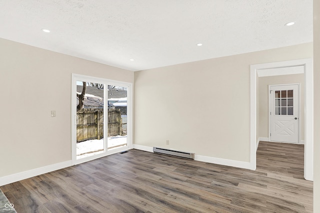 unfurnished room featuring dark hardwood / wood-style floors, a textured ceiling, and baseboard heating