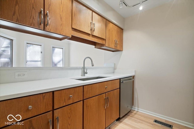 kitchen featuring sink, rail lighting, dishwasher, and light wood-type flooring